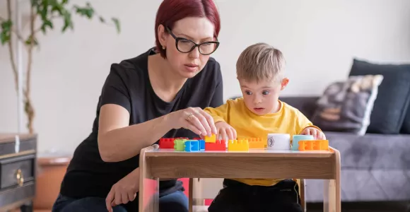 Une maman joue aux cubes avec son enfant porteur d'une trisomie