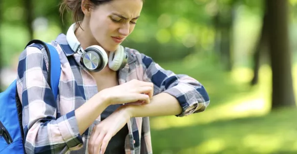 Jeune femme se grattant l'avant-bras gauche en faisant une tête contrariée
