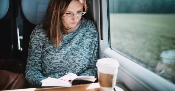 Femme assise dans un train qui lit un livre