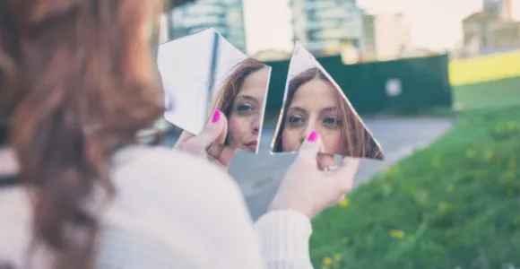 Femme se regardant dans un miroir brisé en 2 morceaux