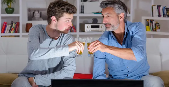 Un père et son fils  trinquent avec des shots d'alcool