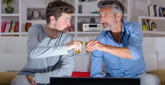 Un père et son fils  trinquent avec des shots d'alcool