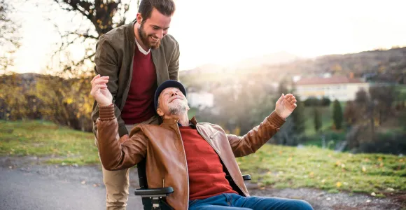 Un jeune homme pousse un vieil homme en fauteuil roulant