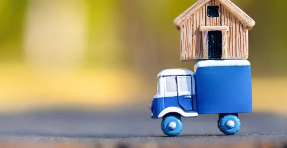 Un petit camion en bois transporte une petite maison en bois