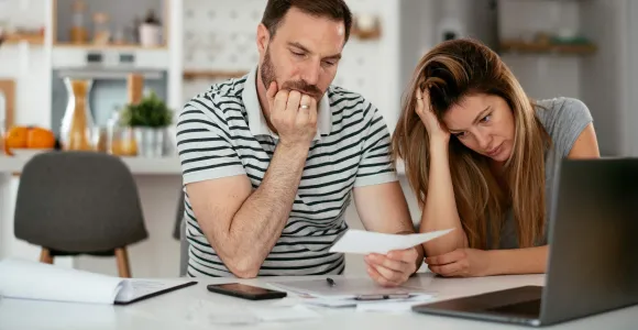 Un couple est dépité en regardant des documents derrière leur ordinateur