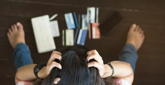Un femme se tient la tête en détresse face à plusieurs cartes de crédit