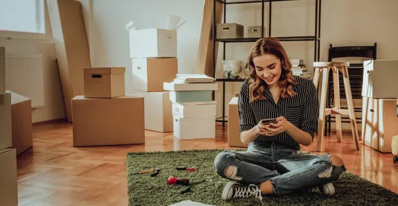 Une jeune femme sur son smartphone est en plein déménagement