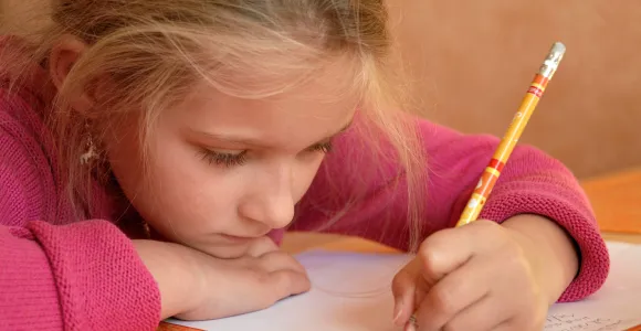 Une petite fille gauchère écrit sur une feuille