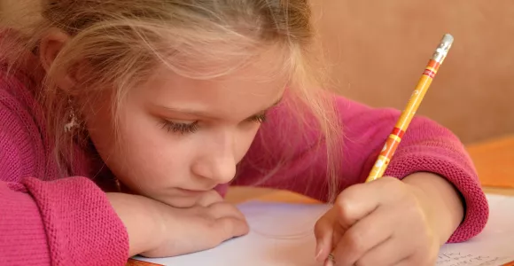 Une petite fille gauchère écrit sur une feuille