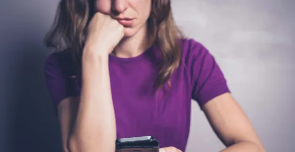 Une femme regarde son smartphone avec dépit