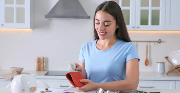 Une femme range des billets dans son portefeuille