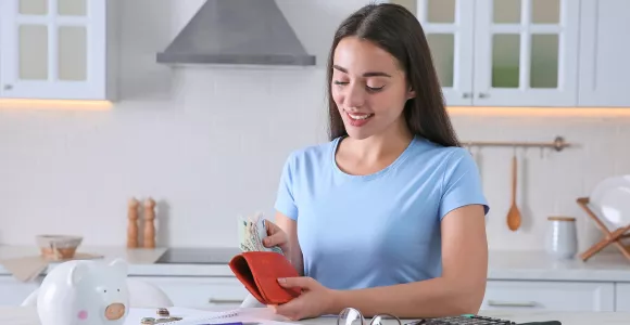 Une femme range des billets dans son portefeuille