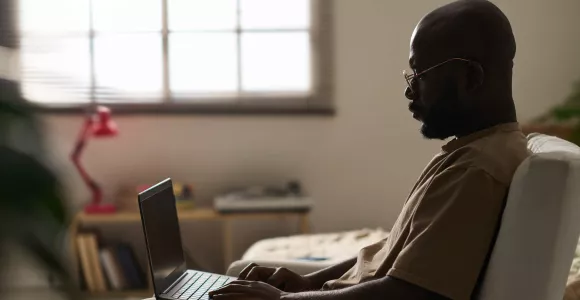 Un homme consulte son ordinateur portable dans un fauteuil