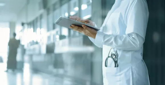 Une prestataire médicale utilise une tablette dans un couloir d'hôpital