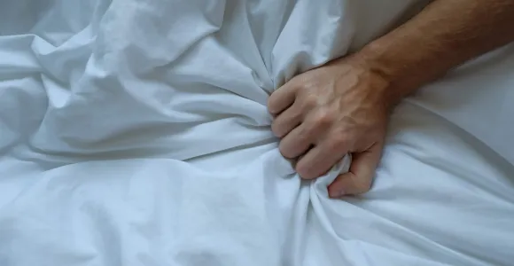 Une main d'homme agrippe une couette blanche
