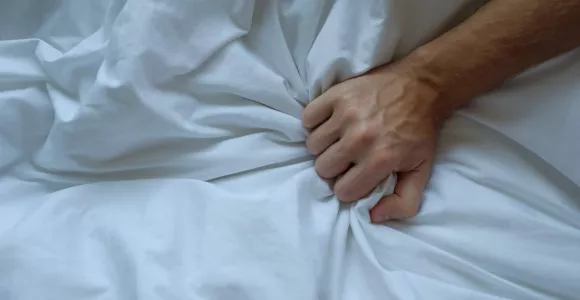 Une main d'homme agrippe une couette blanche