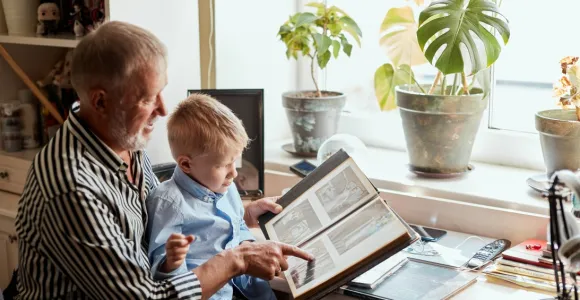 Un grand-père et son petit-fils consultent un album avec des photos de famille
