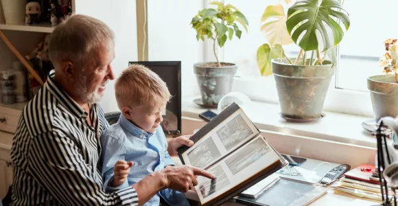 Un grand-père et son petit-fils consultent un album avec des photos de famille