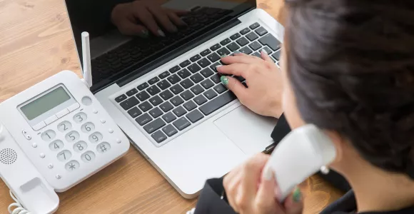 Une femme téléphone pendant qu'elle utilise un ordinateur portable