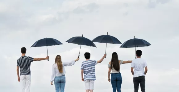 Cinq personnes de dos qui se tiennent un parapluie 