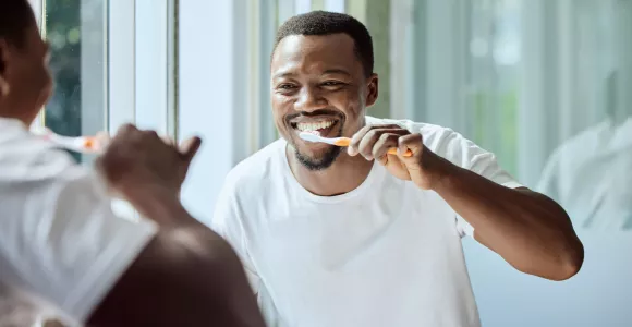 Un homme se brosse les dents devant le miroir