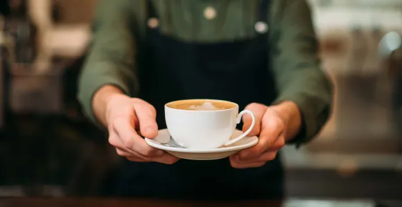 Un barista tend une tasse de café