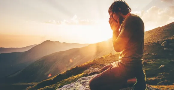 Un homme sur une montagne qui se tient les mains dans le visage