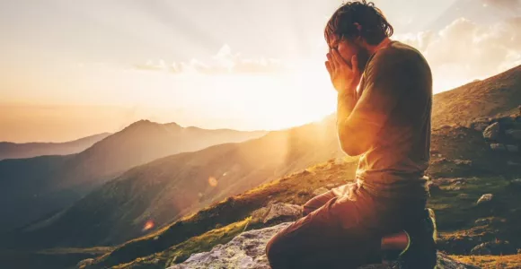 Un homme sur une montagne qui se tient les mains dans le visage