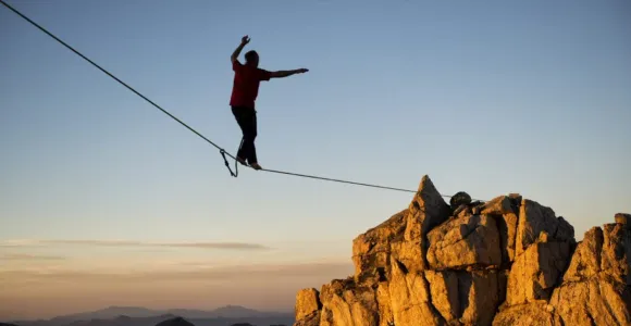 Un équilibriste marche sur un fil tendu vers une montagne