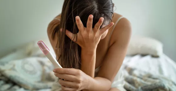Une femme dépitée tient un test de grossesse en main
