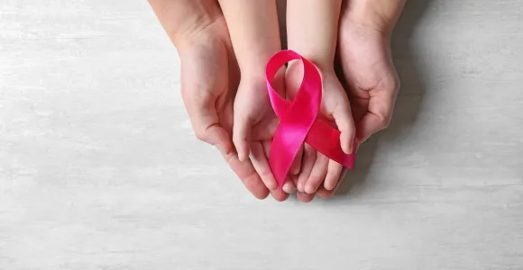 Des mains d'adulte et d'enfant tiennent un ruban rose