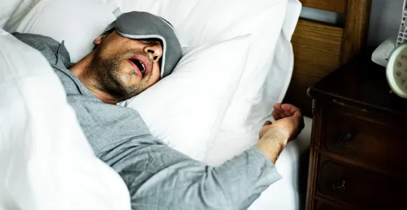 Un homme dort la bouche ouverte.