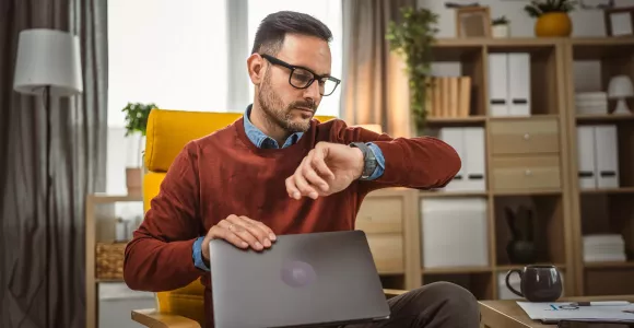 Un homme regarde l'heure en fermant son ordinateur