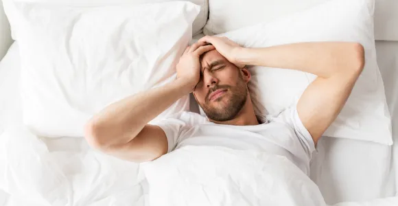 Un homme qui a une insomnie se tient la tête couché dans son lit