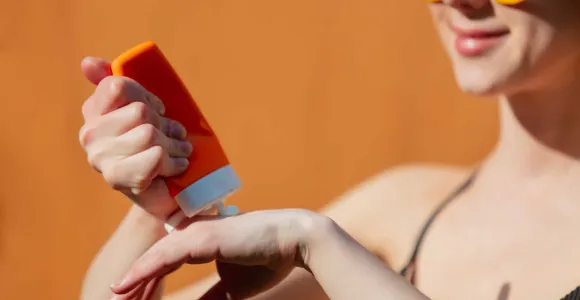 Une femme s'applique de la crème solaire sur la main