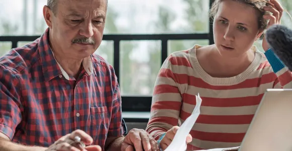 Un homme et une femme assis l'un à côté de l'autre, regardent un document.
