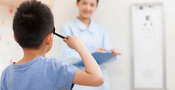 un enfant passe un examen de la vue et déchiffre des lettres au tableau