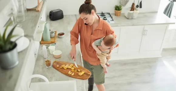 maman qui cuisine avec un bébé dans les bras