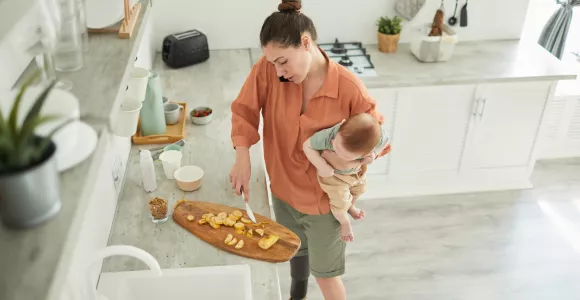 maman qui cuisine avec un bébé dans les bras