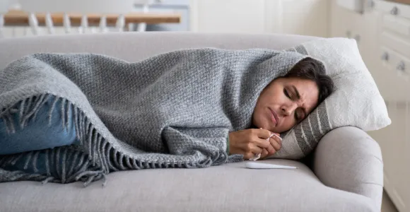 personne malade tenant un thermomètre