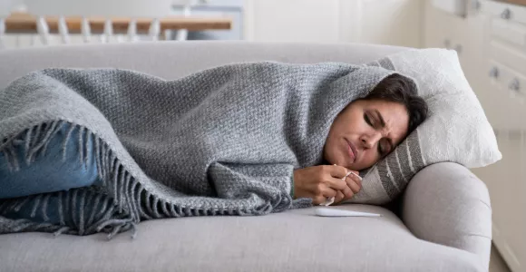 personne malade tenant un thermomètre