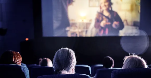dans une salle de cinéma, on aperçoit des personnes de dos et une partie de l'écran de cinéma