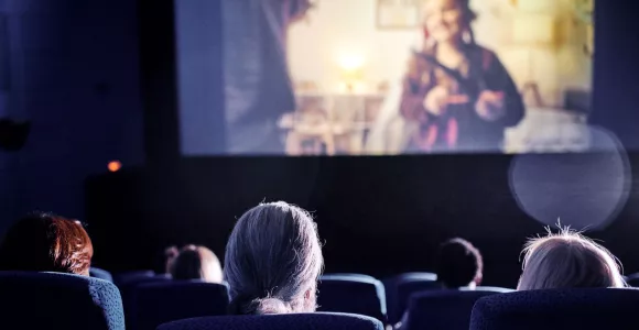 dans une salle de cinéma, on aperçoit des personnes de dos et une partie de l'écran de cinéma