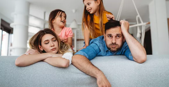 Des parents épuisés par leurs enfants sur un canapé