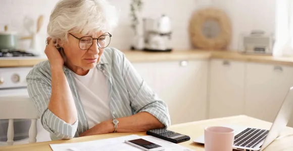 Une femme lit un document, assise à une table