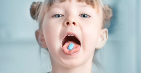une petite fille a un médicament sur la langue
