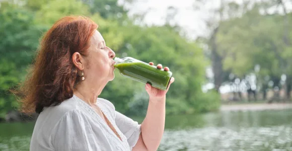 une vieille femme boit un jus de légumes
