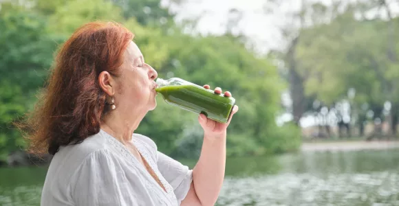 une vieille femme boit un jus de légumes
