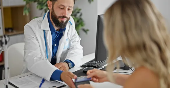 Un médecin montre sa facture à une patiente.