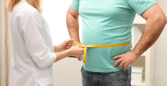 Une médecin mesure le tour de taille d'un patient.